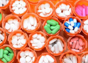 Several pill bottles with pills of varying sizes, shapes, and colors.