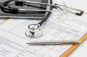 A stethoscope sits on a clipboard with a medical bill attached.